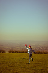 Vintage style effect filter as girl runs outside holding a kite string to fly the kite