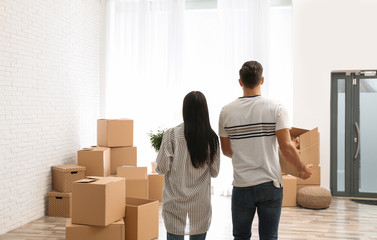 Fototapeta na wymiar Couple in room with cardboard boxes on moving day
