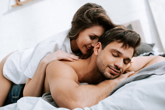 cheerful woman lying on bed with muscular boyfriend