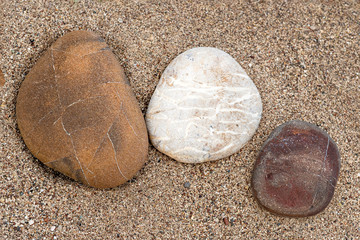 Fototapeta na wymiar Three sea pebbles on a sandy beach close-up.