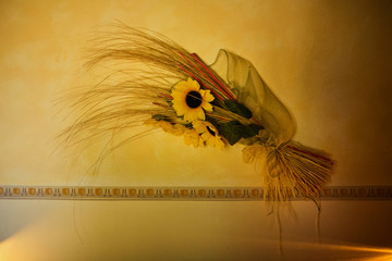 A bouquet of sunflowers on an ochre wall in a country house in Tuscany, Italy, as a traditional...