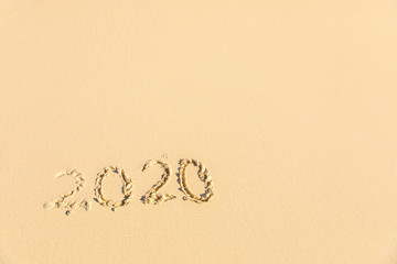 Summer beach holiday 2020 season golden sand - old year - decade - new season lettering on the beach - Numbers 2020 year on the sea shore, message handwritten New Years concept copy empty space