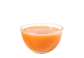 Orange fruit sauce in a glass bowl close-up on a white background