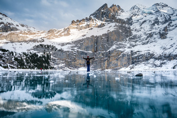 girl in winter outfit looking down on frozen lake Oeschinensee