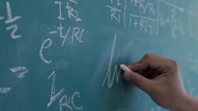 The engineer is calculating the result of the equation to design the electronic circuit, Men writing and sophisticated mathematical formula on chalkboard.