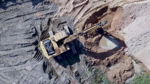 A flying camera takes pictures of an excavator digging sand
