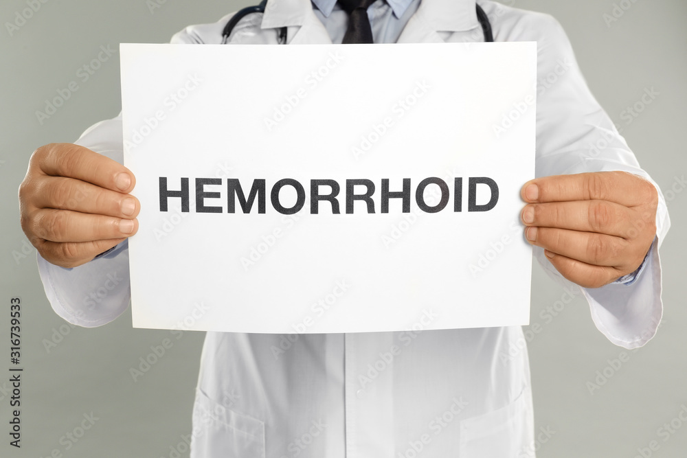 Canvas Prints Doctor holding sign with word HEMORRHOID on light grey background, closeup