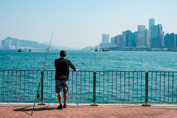 fisher man with fishing rod on coast with skyline background 