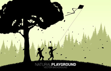 silhouette of boy and girl running with flying kite in the sky with big tree. Concept of children play and learn in natural.