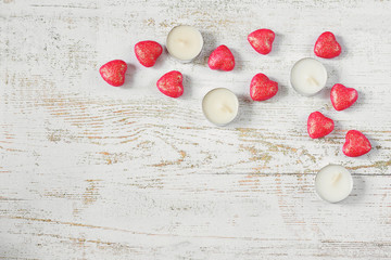 Wooden light background with red hearts and candles. Valentine's day concept.