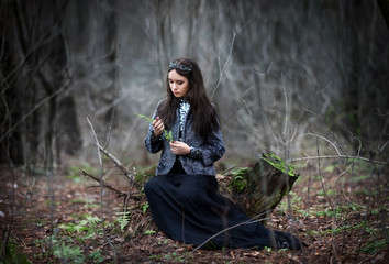 A girl in the image of the dark Queen, a Gothic Princess. In a crown and a long dark outfit in a dark forest. Mystical image © Марина Шавловская