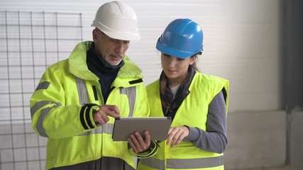 Instructor with apprentice on construction site working with tablet