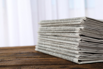 Stack of newspapers on wooden table, space for text. Journalist's work