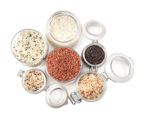 Brown and polished rice in jars isolated on white, top view