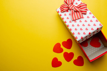 Open gift box with red hearts on a yellow background