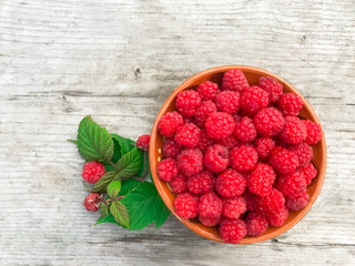 Raspberries. A bowl full of ripe red raspberries on a wooden background. Beautiful concept with berries with copy space.