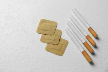 Nicotine patches and cigarettes on white background, flat lay