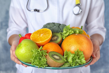 Female nutritionist with fruits and vegetables on light blue background, closeup
