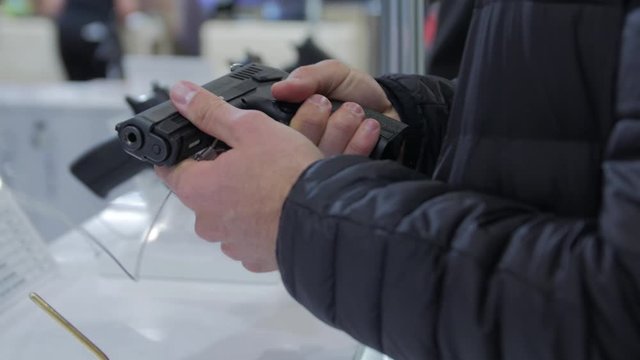 A man buys a gun chooses in a military weapon store hands closeup