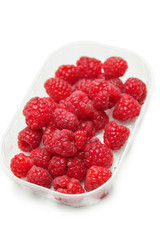 Fresh raspberries in a container against white background