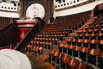 Retro wall clock above entrance and seats in circus