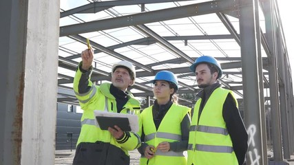 Engineering instructor working on building site with apprentice