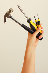 Hammer and screwdriver in hand on white background. Construction tools at arm's length