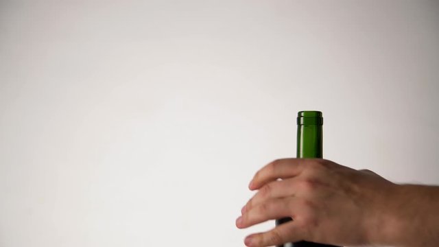 Sommelier opening red wine bottle on white background. Man hands pulling cork out of the bottle using opener
