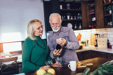 Senior couple in love in the kitchen and drinking wine.