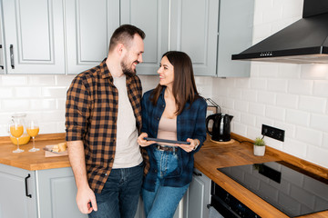 Girl with a tablet and a guy in the kitchen