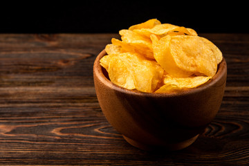 Crisps on dark wooden background.