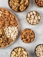 Variety of nuts in wooden plate on grey concrete background. Mixed nuts in wooden bowl. Almond, walnut, peanut, cashew, hazelnut, pistachio. Top view ingredients.