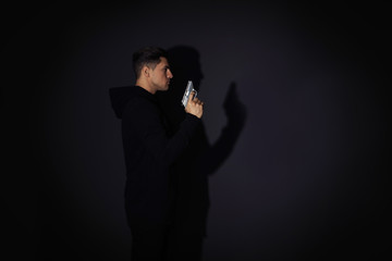 Professional killer with gun on black background. Space for text