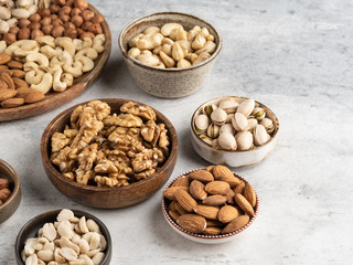 Variety of nuts in wooden plate on grey concrete background. Mixed nuts in wooden bowl. Almond, walnut, peanut, cashew, hazelnut, pistachio. Top view ingredients.