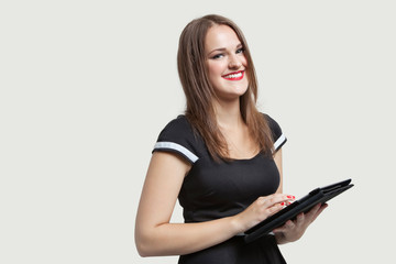 Portrait of a happy woman using tablet PC over gray background