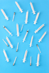 Medical syringes with needles on a blue background. Vertical orientation, top view.