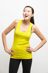 Naklejka premium Happy young woman in yellow tank top with hands on hips looking away against white background