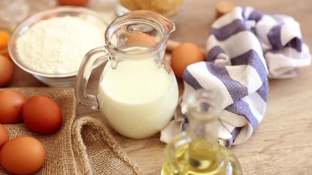Footage  of ingredients prepared to make pastry. Eggs, milk, flour on table top view shot. Slow motion video.
