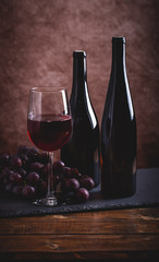Glass of Red Wine and Two Bottles