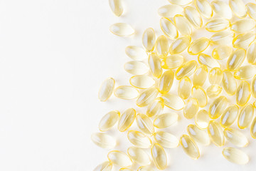 Transparent yellow vitamin capsules on a light pastel background. The concept of health, beauty. Vitamin E, omega-3, vitamin D3, fish oil. Top view, minimalism, copy space.