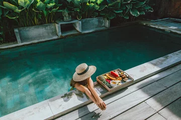 Foto op Plexiglas Meisje ontspannen en fruit eten in het zwembad op luxe villa in Bali © Alena Ozerova