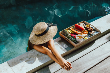 Girl relaxing and eating fruits in the pool on luxury villa in Bali