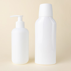 Two white cosmetic bottles without labels on a light pastel background. Bottle for mockup, copyspace, minimalism. The concept of beauty, cosmetology.