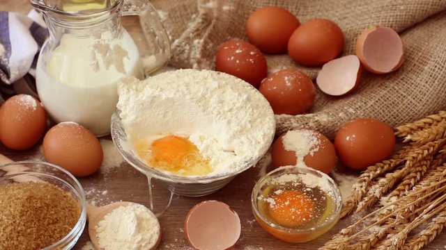 Footage  of ingredients prepared to make pastry. Eggs, milk, flour on table top view shot. Slow motion video.