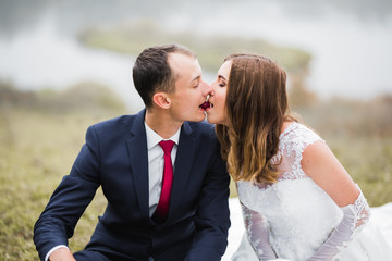 Beautiful bride and groom embracing and kissing on their wedding day outdoors