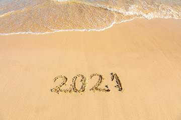 New Year 2021 is coming - inscription 2021 on a beach sand, the wave is starting to cover the digits - Summer beach holiday 2021 season golden sand - old year - message handwritten - empty copy space