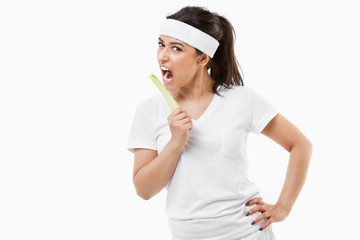 Portrait of young sportswoman eating celery over white background