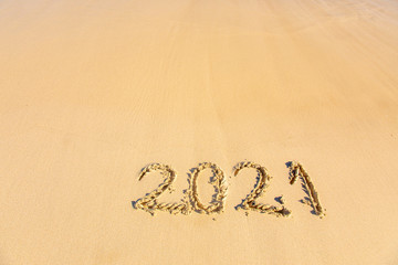 New Year 2021 is coming - inscription 2021 on a beach sand - Summer beach holiday 2021 season golden sand - old year - message handwritten - empty copy space