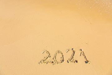 New Year 2021 is coming - inscription 2021 on a beach sand - Summer beach holiday 2021 season golden sand - old year - message handwritten - empty copy space