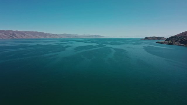 Aerial drone shot circular of Lake Sevan on background of Mount Ararat. Aerial drone zoom in shot of Lake Sevan under bright blue sky